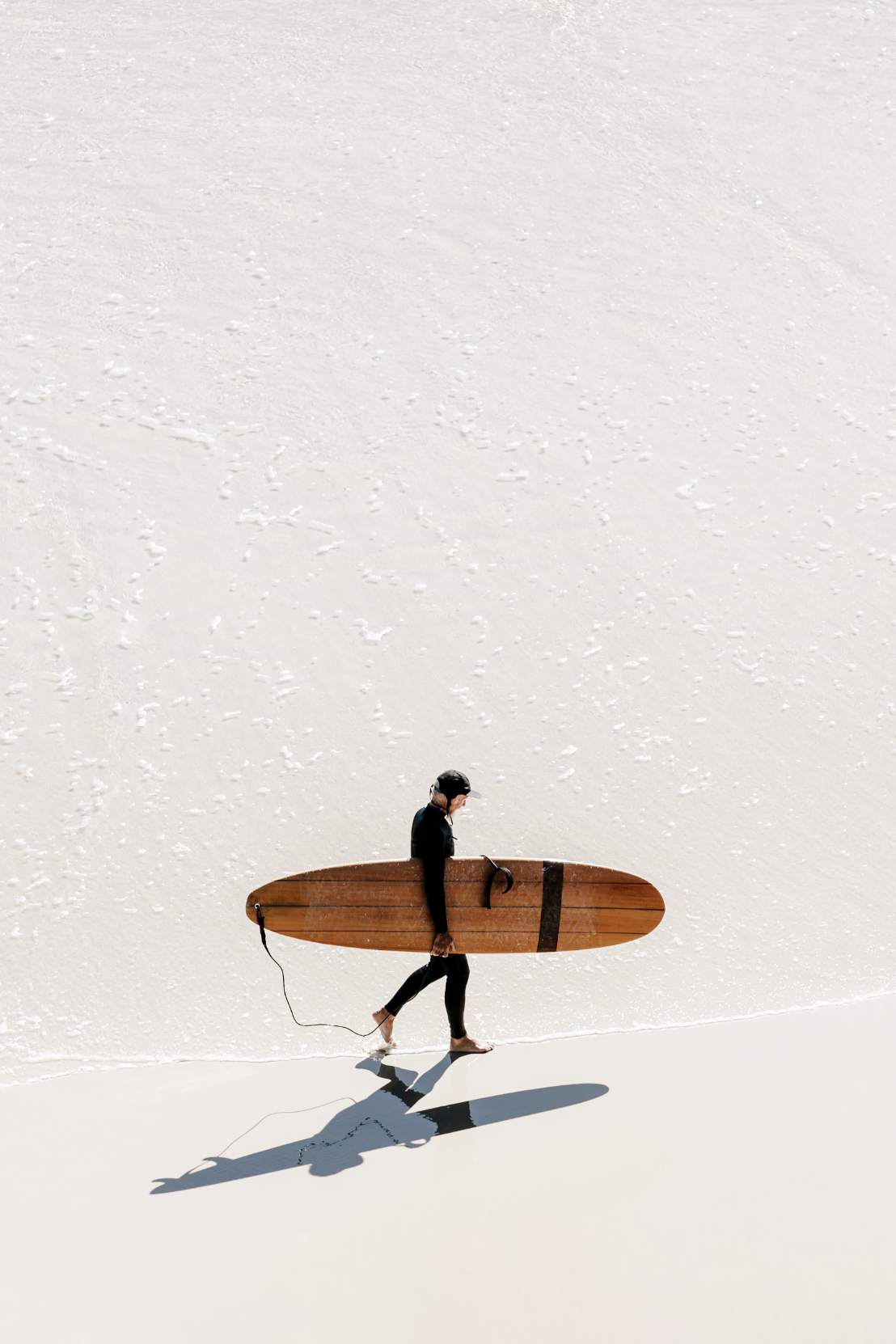 Australian Prints by Mackenzie Sweetnam. A lone surfer walks along the shoreline in Queensland, Australia.
