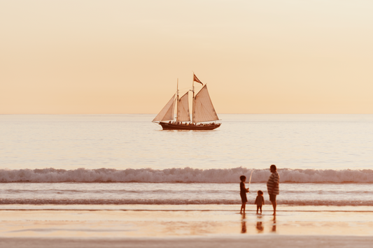 Australian Prints by Mackenzie Sweetnam. A photographic print of ship sailing at sunset along with a family fishing in the foreground in Broome.