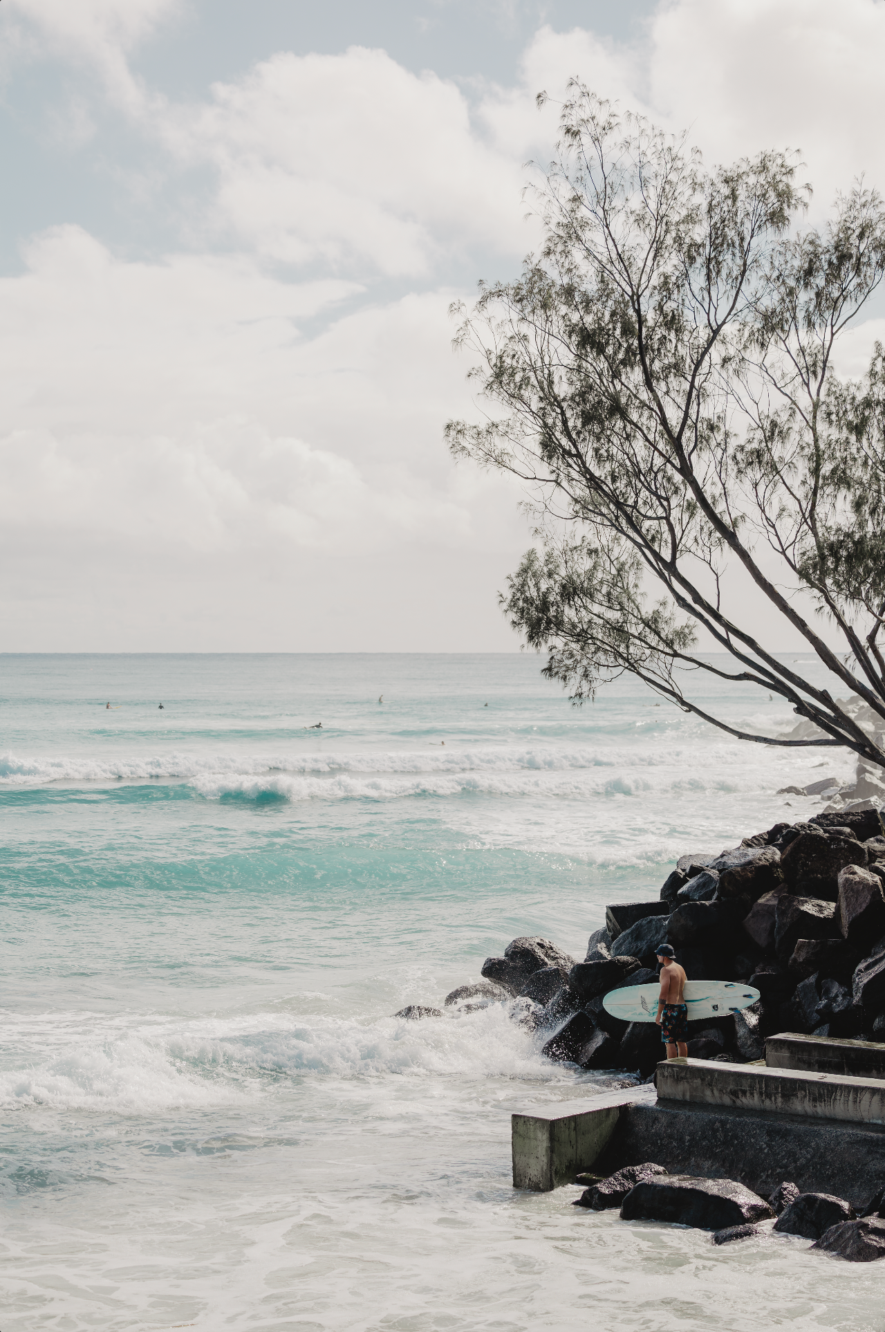 Australian Prints by Mackenzie Sweetnam. A surfer waits for the perfect moment to jump into the ocean with his surfboard in Queensland, Australia.